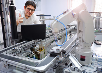 The Scientist working on laptop to program smart factory prototype's automation in a laboratory. Industry 4.0 concept; artificial intelligence in smart factory.