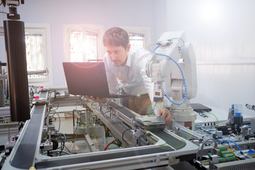 The Scientist working on laptop to program smart factory prototype's automation in a laboratory....