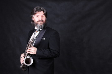 A male artist musician in a classic black suit, tailcoat, statuesque in a bow tie with a beard...