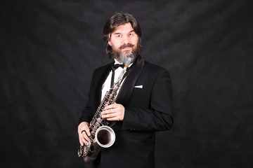 A male artist musician in a classic black suit, tailcoat, statuesque in a bow tie with a beard...