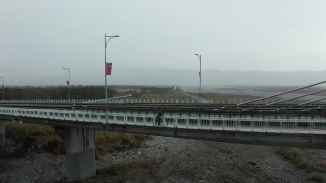 Aerial drone closing shot of biker on a bridge in Taiwan