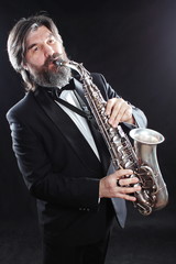 A male artist musician in a classic black suit, tailcoat, statuesque in a bow tie with a beard...