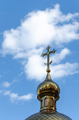 Fototapeta na wymiar Golden dome with a cross of the Orthodox Church against the blue sky. Outdoors. Religion concept. Copy space.