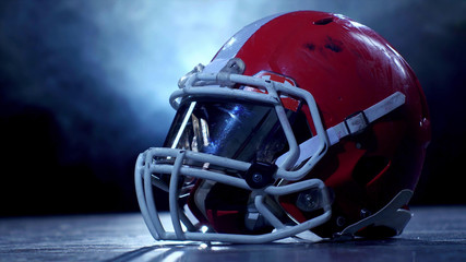 American football player red helmet, close up on a dark background with smoke