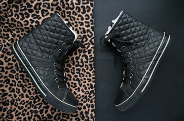 Trendy black quilted leather sneakers on two contrast backgrounds. Animal print and minimalist...