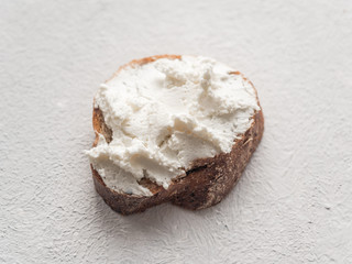 Whole grain bread bruschetta with white soft curd cream cheese on a white background. Close-up
