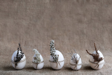 Zero waste, vegan, sustainable Easter concept. Row of eggs decorated with dried flowers on natural...