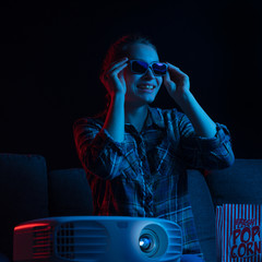 Girl watching movies on the couch with popcorn. Cinema and films. Home cinema. Watching films at home in 3D. Square photo