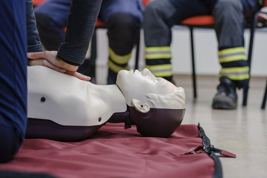 Person learning the methods of lifesaving actions by restarting the heart on a manequin