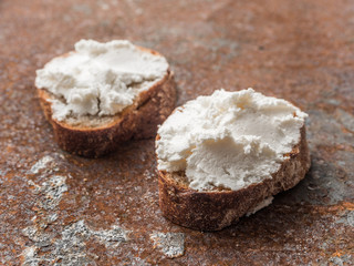 Whole grain bread bruschetta with white soft curd cream cheese on a ginger grunge background. Close-up