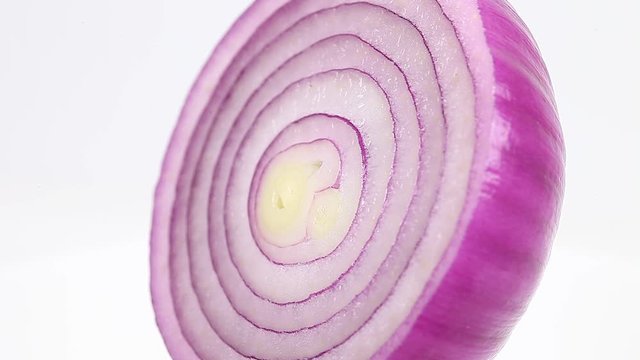 Red onion cut in half rotates spins around its axis, fresh juicy vegetable. Macro close-up video footage.