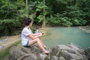 young cute hipster girl travelling at beautiful Erawan waterfall mountains  green forest hiking views at Kanchanaburi, Thailand. guiding  idea for female backpacker woman women backpacking