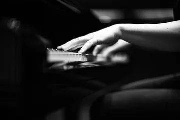 Graustufenaufnahme der Hände einer Person, die Klavier spielt © Erik Witsoe/Wirestock