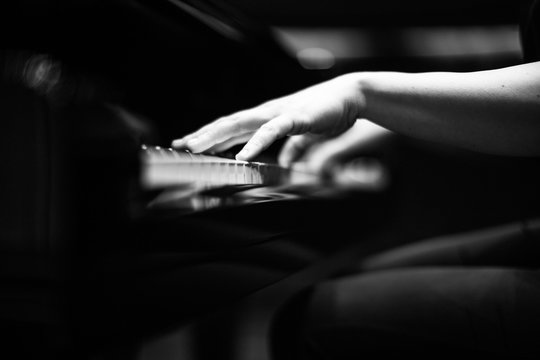 Grey scale shot of a the hands of a person playing the piano