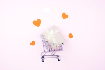 Shopping cart and gift with hearts on a pink background