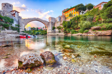 Fantastic Skyline of Mostar with the Mostar Bridge, houses and minarets, at sunset - obrazy, fototapety, plakaty