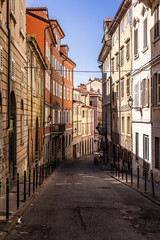 Fototapeta na wymiar Narrow empty street 'via felice venezian' in old town trieste in Italy. Facades of old and colorful mediterranean houses visible.