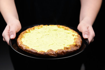 Omelet in female hands on black background. Woman holds a plate with omelette from chicken eggs