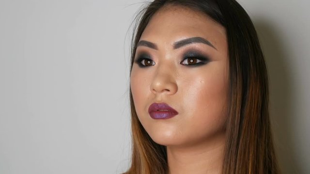 Portrait of a beautiful Asian girl model with bright makeup who poses in a professional studio