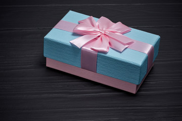 blue gift box tightened by a pink ribbon on a black background