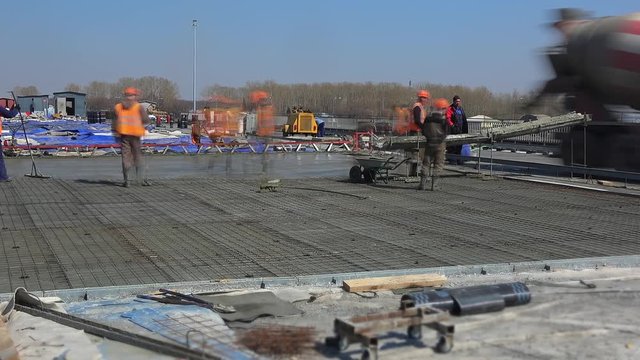 Timelapse workers build a new concrete road. It's pouring concrete from mixer