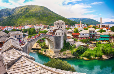 Fantastic Skyline of Mostar with the Mostar Bridge, houses and minarets, during sunny day. - obrazy, fototapety, plakaty