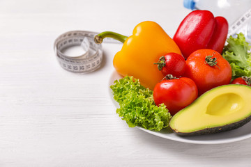 Different healthy food with measuring tape on white wooden background. Diet concept