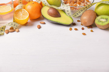 Different healthy food with measuring tape on white wooden background. Diet concept
