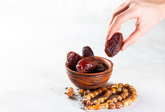 Plate with dates, decorative arabic lantern and rosary on a light background. Holy month of Ramadan concept. Children's hand reaches for a plate with dates.