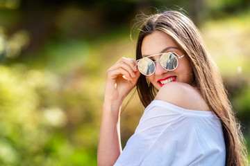 Outdoor portrait of beautiful, emotional, young woman in sunglasses. Soft background. Copy space.