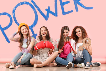 Young women near color wall with word POWER. Concept of feminism