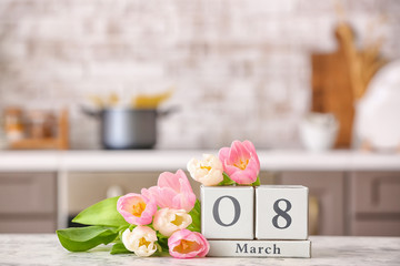 Fototapeta na wymiar Calendar with date of International Women's Day and flowers on table in kitchen