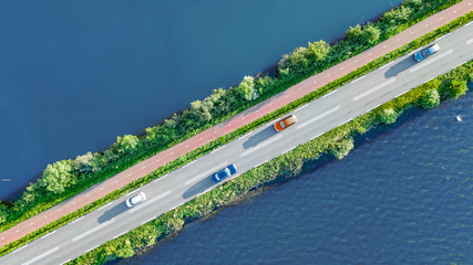 Aerial drone view of motorway road and cycling path on polder dam, cars traffic from above, North...