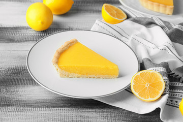 Plate with slice of tasty homemade lemon pie on table