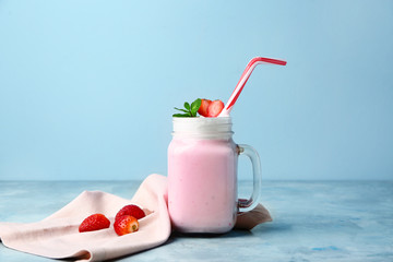 Mason jar of tasty milkshake on color background