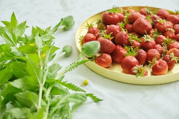 Berries of red ripe strawberry on white table in golden tray