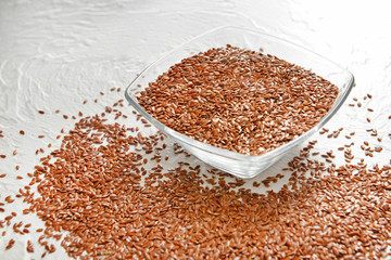 Bowl with flax seeds on white background