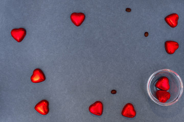 Red hearts shaped sweets, ..chocolates with coffee grains on a grey background. Greeting card Happy Valentines Day. Copy space. Top view.