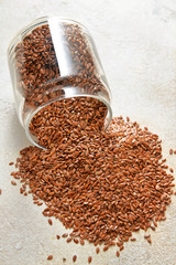 Overturned jar with flax seeds on light background