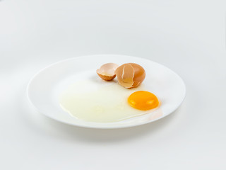 Broken eggs on a plate white background. reddish yellow