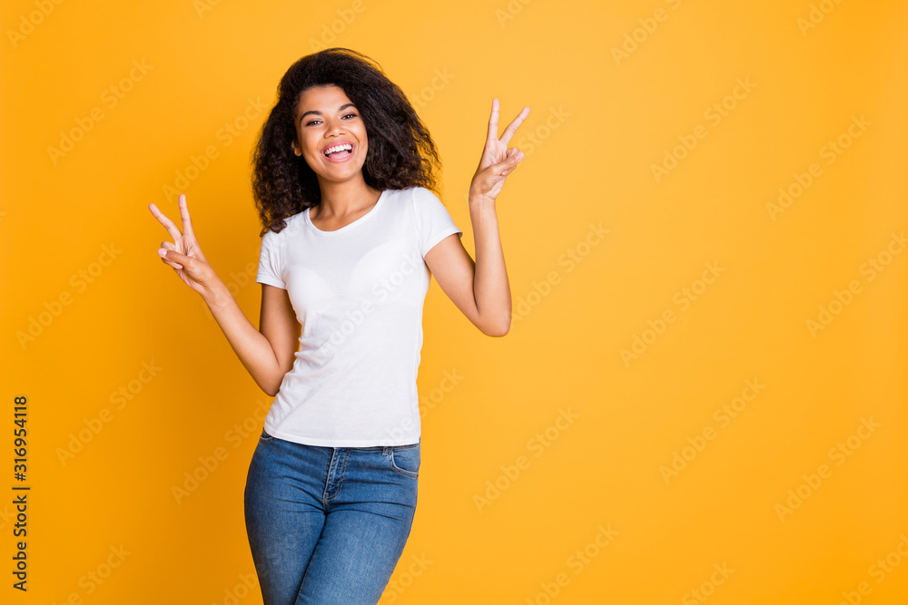 Sticker Photo of curly wavy cheerful positive nice pretty girlfriend showing double v-sign in jeans denim white t-shirt near empty space isolated vivid color background