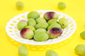 natural fresh green and burgundy olives in a white decorative plate on a yellow background