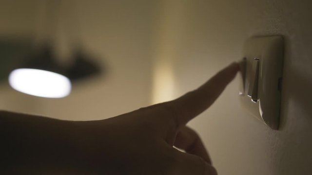 Close up hand switch off electric light . Concept of energy and power saving.