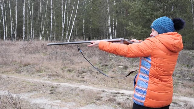 Beautiful woman shoots a hunting rifle in nature