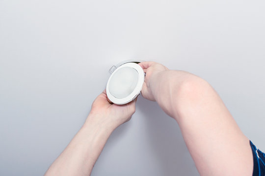 Installing spots. Electrician  installing or replacing spot light lamp into ceiling. Installing a spot in a stretch ceiling.