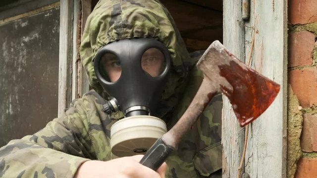 A Man  Axe Murderer  In A Gas Mask with bloody axe look toward camera  ready to kill. Apocalypse  Murderer  concept