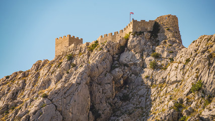 The evening sun illuminates the medieval pirate fortress Stari Grad, located at an altitude of 260 meters, in the city of Omis, Croatia