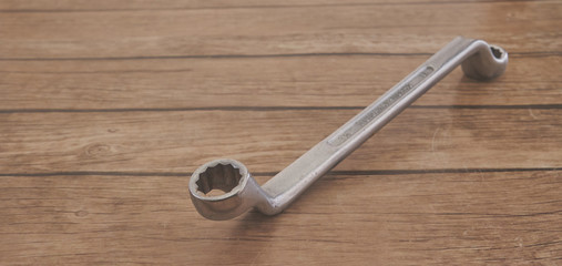 old silver metal wrench for fixing rusted cars on a wood table background