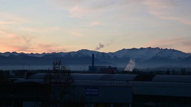 Turin, Gerbido, Piedmont, Italy January 2020. The waste-to-energy plant of the IREN company. In the background the Piedmont Alps. Pan shot. The smog at the foot of the mountains is clearly visible.