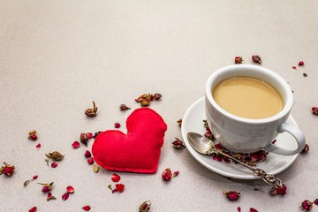 Good morning. Cup of coffee, rose buds and petals, red felt heart. Romantic breakfast, Valentine's Day. Stone concrete background